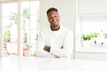 Handsome african american man on white table happy face smiling with crossed arms looking at the camera. Positive person.
