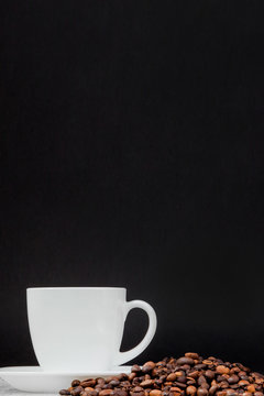 Black coffee in white cup and coffee beans on black background. Top view, space for text