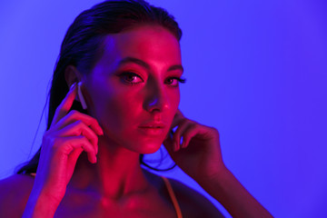 Image of young sensual woman wearing bodysuit underwear listening to music with earpods