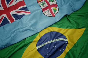 waving colorful flag of brazil and national flag of Fiji .