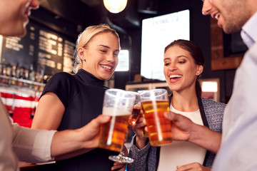 Male And Female Friends Making A Toast As They Meet For Drinks And Socializing In Bar After Work