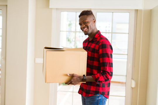 Young african american man holding a carton box, packing cardboard delivery package at home
