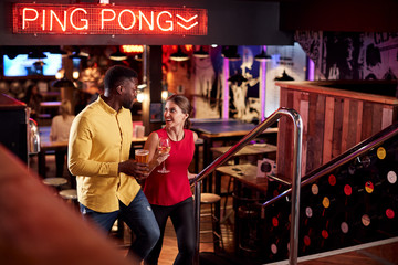 Couple On Date Climbing Stairs As They Meet For Drinks And Socialize In Bar