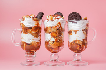 Sweet dessert in glass with biscuit and whipped cream on pink bsckground, selective focus and blank space