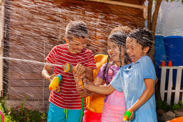 Kids play shooting water gun game, hot summer day