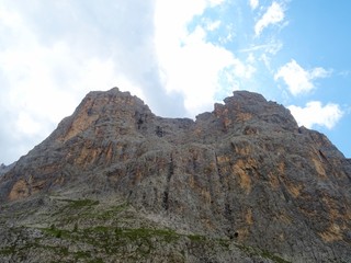 Fototapeta na wymiar The peaks of the Dolomites of the Sassolungo Massif immersed in the clouds and in the nature of Trentino - Alto - Adige, Near the town of Canazei, Italy - August 2019.