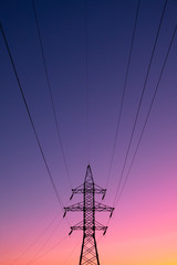 Electric power lines in the evening sun. Electric energy transmission pole in vibrant background,...