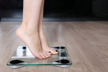 Female legs on a scales, slimming and diet. Woman measuring her weight at home standing on tiptoe, weight loss concept