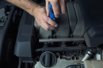 Man fixes car in a car service. Engine repair, maintenance, service.