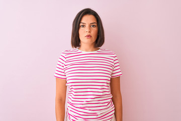 Fototapeta premium Young beautiful woman wearing striped t-shirt standing over isolated pink background Relaxed with serious expression on face. Simple and natural looking at the camera.