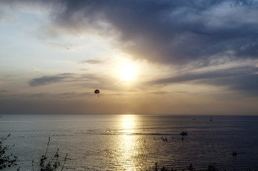 skydiver flying over the sea on the background of the setting sun