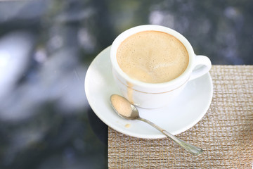 Coffee with foam on a saucer with a spoon and careless drip