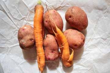 Young potatoes and carrots on a paper background. The concept of autumn harvest, fresh organic products, vegetarianism.