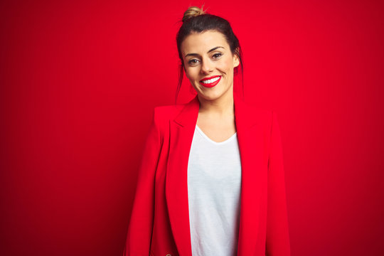 Young beautiful business woman standing over red isolated background with a happy and cool smile on face. Lucky person.