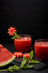 Watermelon smoothie fresh juice with mint and pieces in the shape of stars on a black background. Summer healthy drinks. Copy space.