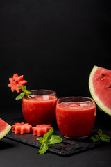 Watermelon smoothie fresh juice with mint and pieces in the shape of stars on a black background. Summer healthy drinks. Copy space.