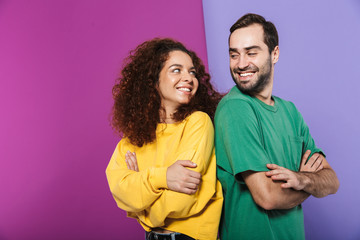 Portrait of brunette caucasian couple man and woman in colorful clothing smiling at each other...