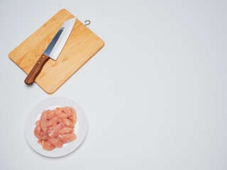 Fresh chicken tenderloin with wooden board, knife.