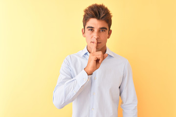 Young handsome businessman wearing elegant shirt over isolated yellow background asking to be quiet with finger on lips. Silence and secret concept.