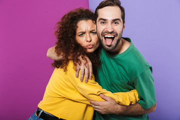 Portrait of happy caucasian couple man and woman in colorful clothing rejoicing and hugging together