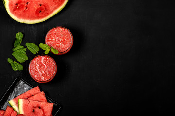 Watermelon smoothie fresh juice with mint and pieces in the shape of stars on a black background. Summer healthy drinks. Copy space. Top view.