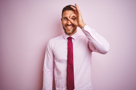 Business man wearing tie and elegant shirt over pink isolated background doing ok gesture with hand smiling, eye looking through fingers with happy face.