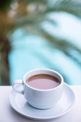 Coffee with milk in a white cup on the balcony of the hotel. The concept of rest and relaxation