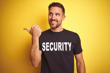 Young safeguard man wearing security uniform over yellow isolated background smiling with happy...