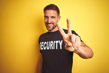 Young safeguard man wearing security uniform over yellow isolated background smiling looking to the...