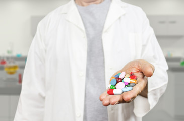 Old doctor holding pills, capsules, drugs and medics on a blurred laboratory background 3d rendering. Medicine, health care, overmedication and disease healing concept.