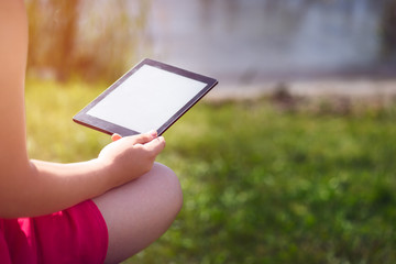 Young girl is reading ebook on the bench near the sea