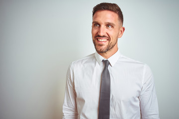 Young handsome business man wearing elegant white shirt over isolated background looking away to side with smile on face, natural expression. Laughing confident.