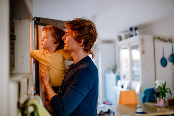 A young father with a toddler son in a kitchen at home.