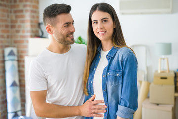 Fototapeta premium Beautiful young couple moving to a new house, smiling happy arround cardboard boxes