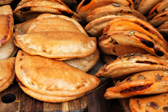 traditional spanish empanadillas, baked dumplings with different stuffings on wooden table