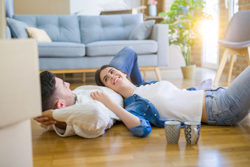 Young beautiful couple lying on the floor of new house, smiling in love very happy for moving to new apartment