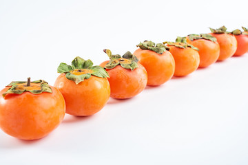 Row of red persimmons with fresh fruits on white background