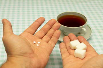 three small sweetener tablets replacing three teaspoons of sugar in hand for adding to a cup of tea