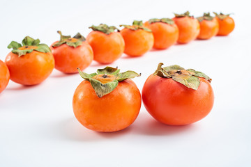Row of red persimmons with fresh fruits on white background