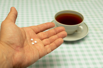 three small sweetener tablets replacing three teaspoons of sugar in hand for adding to a cup of tea