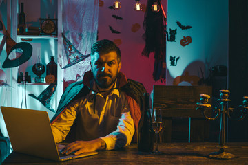 Obraz premium Online shopping for Halloween. Discounts on the Internet before the holiday. October sale. Black Friday. A man with a laptop in a wizard costume.