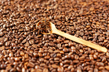 Wooden spoon with anise stars on a background of roasted coffee beans. Coffee and spices, oriental...