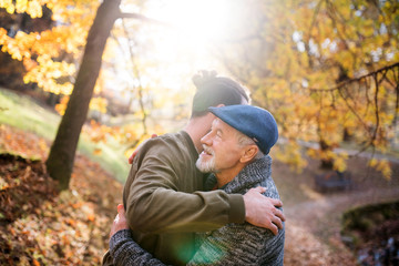 Senior father and his son on walk in nature, hugging.