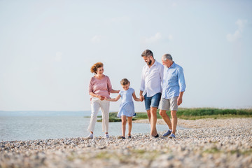 Multigeneration family on a holiday walking by the lake, holding hands.