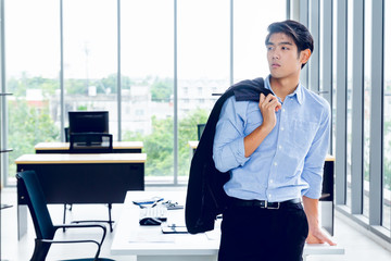 Young Asian Businessperson is standing smart poses and smile at co working space decorated in...