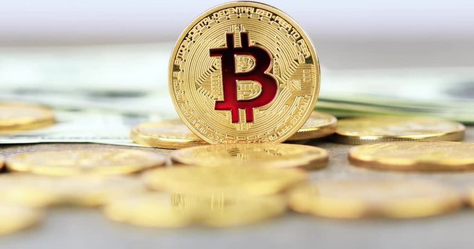 Coin approaching. The cryptocurrency Bitcoin coin. Gold coin. 100 dollar bills lie on the background. Camera movement.