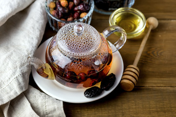 Glass Teapot of Herbal Dog Rose Tea With Dried Rosehips, Types Rosa Canina Hips Hot Drink of Medicinal Plants and Herbs Wooden background Horizontal Honey
