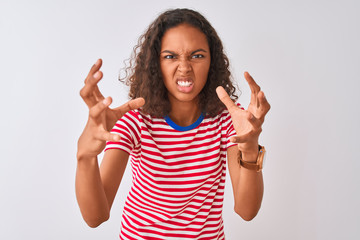 Young brazilian woman wearing red striped t-shirt standing over isolated white background Shouting frustrated with rage, hands trying to strangle, yelling mad