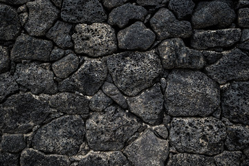 Black volcanic stone wall.Dark rock texture background