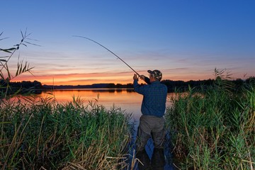 Angler catching the fish during sunset